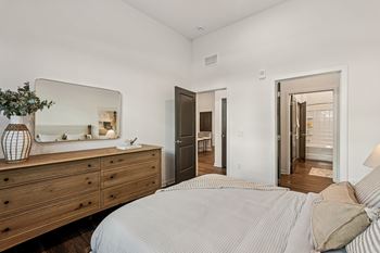 A bedroom with a bed, dresser, and mirror